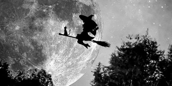 Silhouette of stereotypical Halloween witch and cat riding a broom against a full moon.