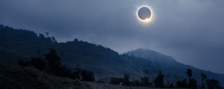 Total solar eclipse over a foggy mountain landscape.