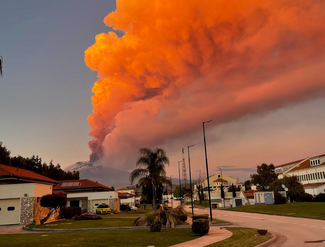 Erupting volcano with a large orange plume of smoke in the distance. 