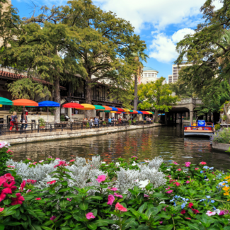Sun shines and flowers bloom on the multicolored umbrellas of the San Antonio, TX Riverwalk