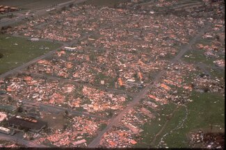 Aerial image of blocks of destroyed homes in Dade County (now Miami-Dade County), FL. Large amounts of debris are scattered across the area and trees are completely stripped.