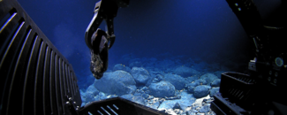 Photo of underwater robotic arm collecting sample from ocean floor