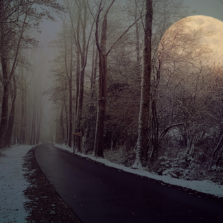 Road winding through a snowy landscape with the full moon in close focus on the right.
