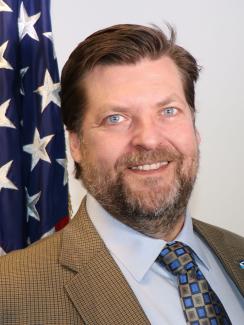 Photo of NCEI Director Deke Arndt in front of an American flag
