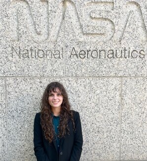 Headshot of NASA DEVELOP team lead Kelli Roberts in front of a stone wall with text “NASA” in the background.