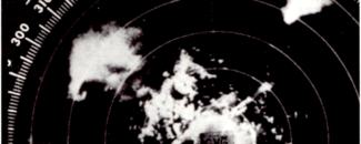 Black and white image of storms on WSR-57 radar scope on April 3, 1974. A “hook echo” or hook-shaped storm cell indicating a severe and potentially tornadic storm can be seen in the upper left corner of the image.