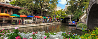 Sun shines and flowers bloom on the multicolored umbrellas of the San Antonio, TX Riverwalk