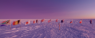 Eleven flags of world countries stood up on poles in the snow tundra near   the iconic candy-striped marker at the South Pole during sunrise in September 2021.
