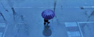 Image of person under umbrella on rainy street