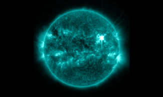 Image of a solar flare blazingly hot in the upper right of the sun