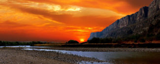 Photo of sunset over Rio Grande River and mountains