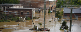 Asheville, NC Devastation from Helene Large brick buildings in the River Arts District in Asheville, NC are submerged in floodwaters, with debris scattered in the water and trees submerged up to the tops of the leaf canopies. Power lines are damaged and strung across the foreground just above the floodwaters.